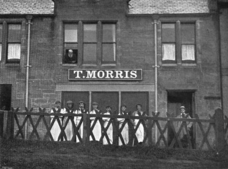 Shopfront reading T. Morris in St Andrews, with workmen standing behind a fence